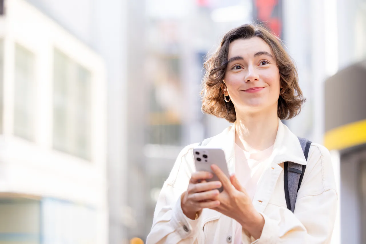 街なかでスマートフォンを見る海外からの観光客