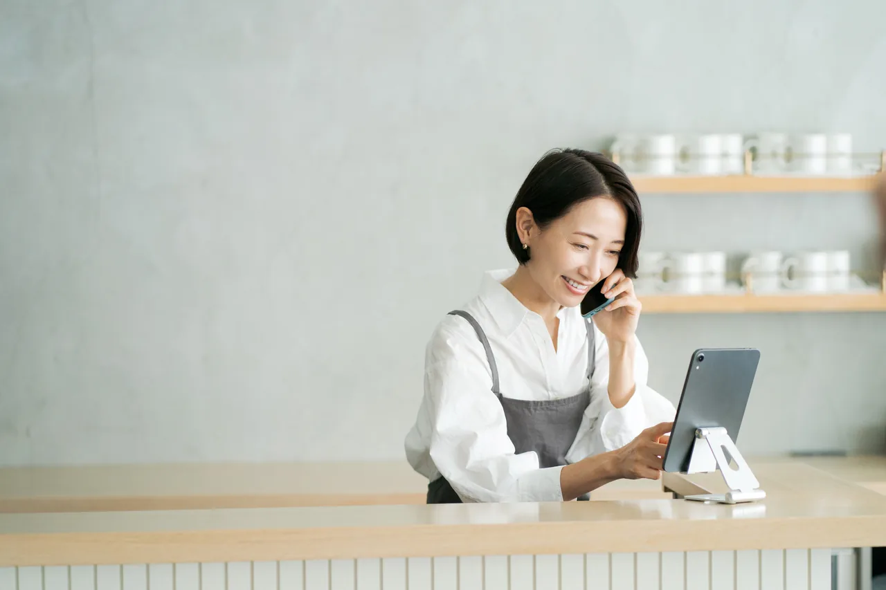 店内で電話を受けながら予定を確認する店主